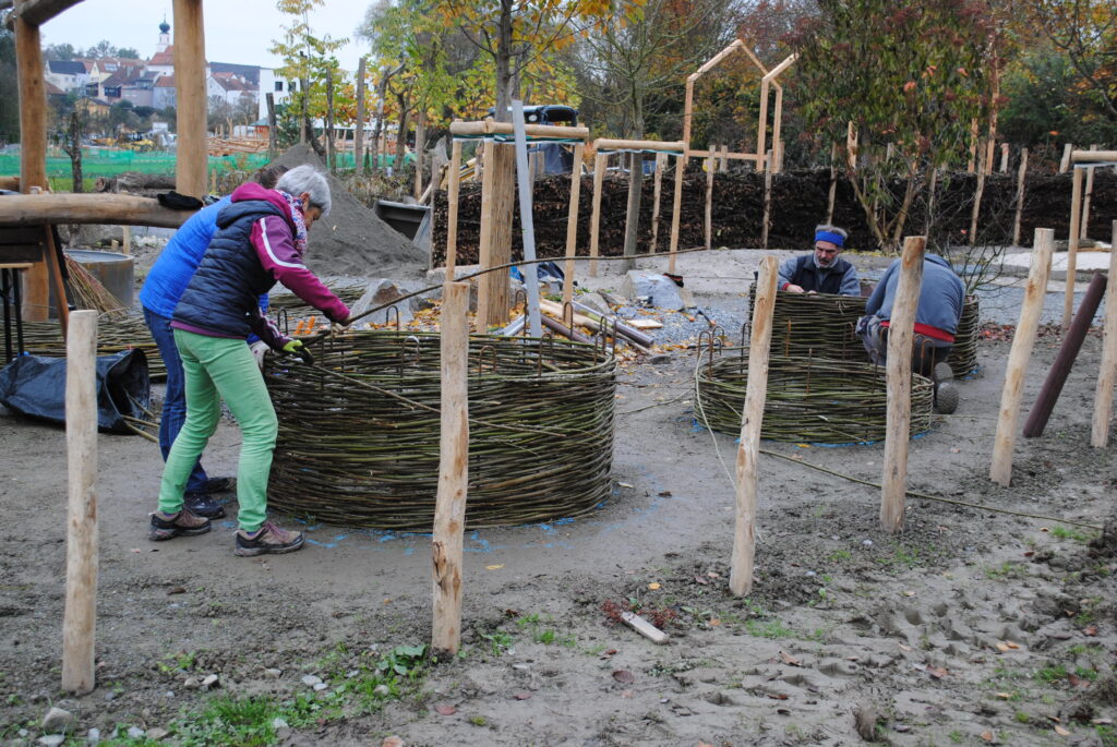 Arbeiter bauen aus Weidenruten runde Hochbeete